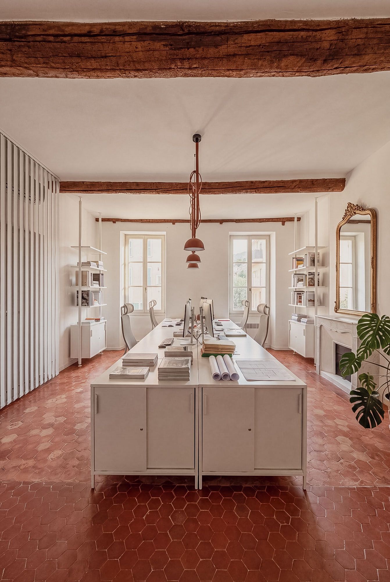 Atelier de Sarkisian Touzet Architecture à Villefranche-sur-Mer : grande table de travail partagée, poutres en bois apparentes, tomettes provençales.